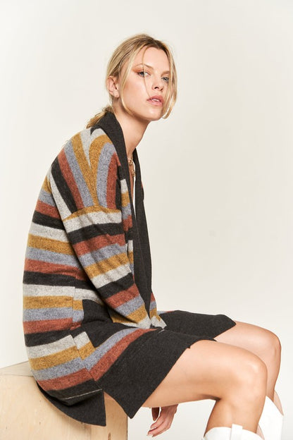 Model sitting wearing Vinni Multi Color Stripe Cardigan with black trim and patch pockets