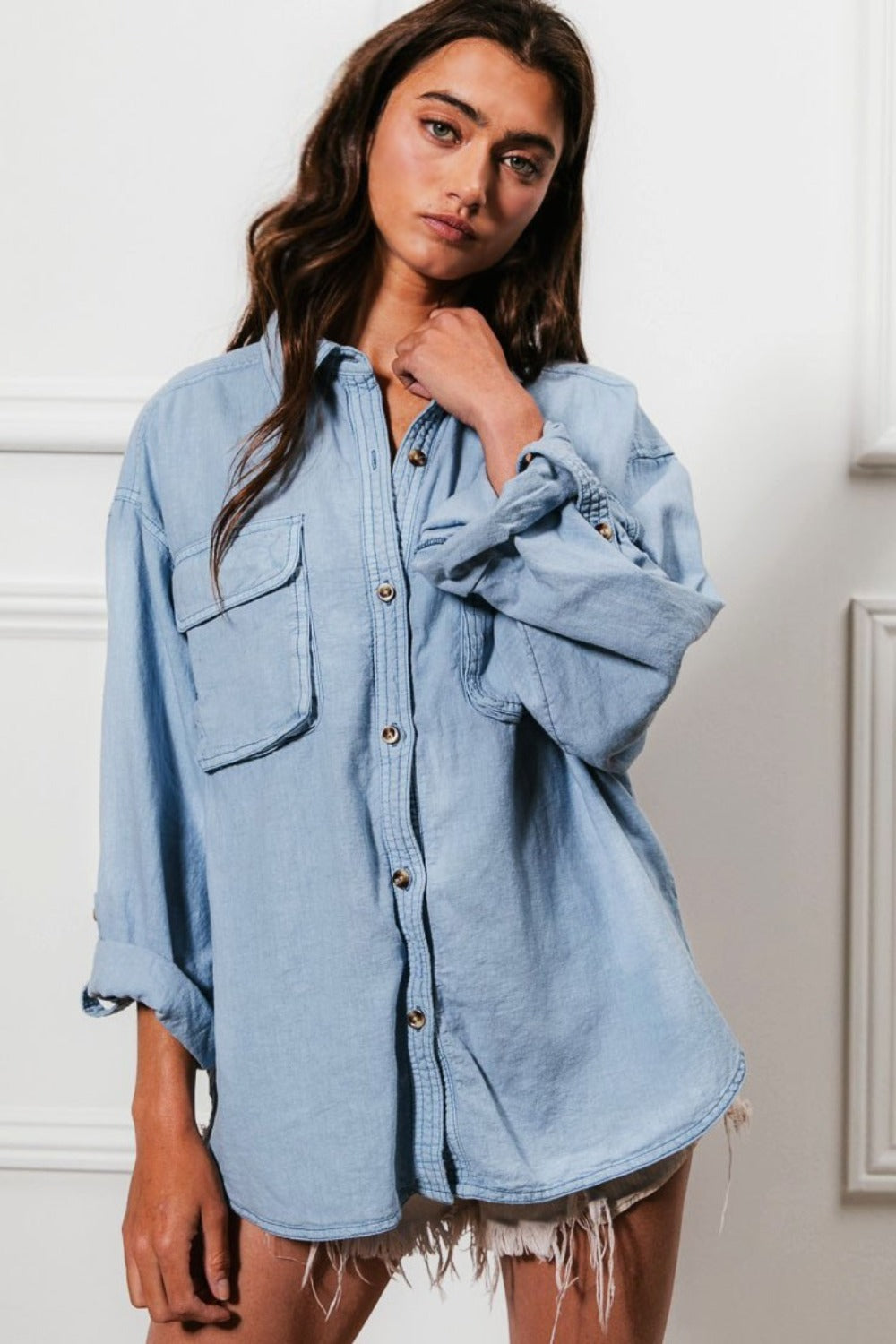 A denim button-down shirt with long sleeves, chest pockets, and detailed stitching. The shirt has a collared neckline and button closure.