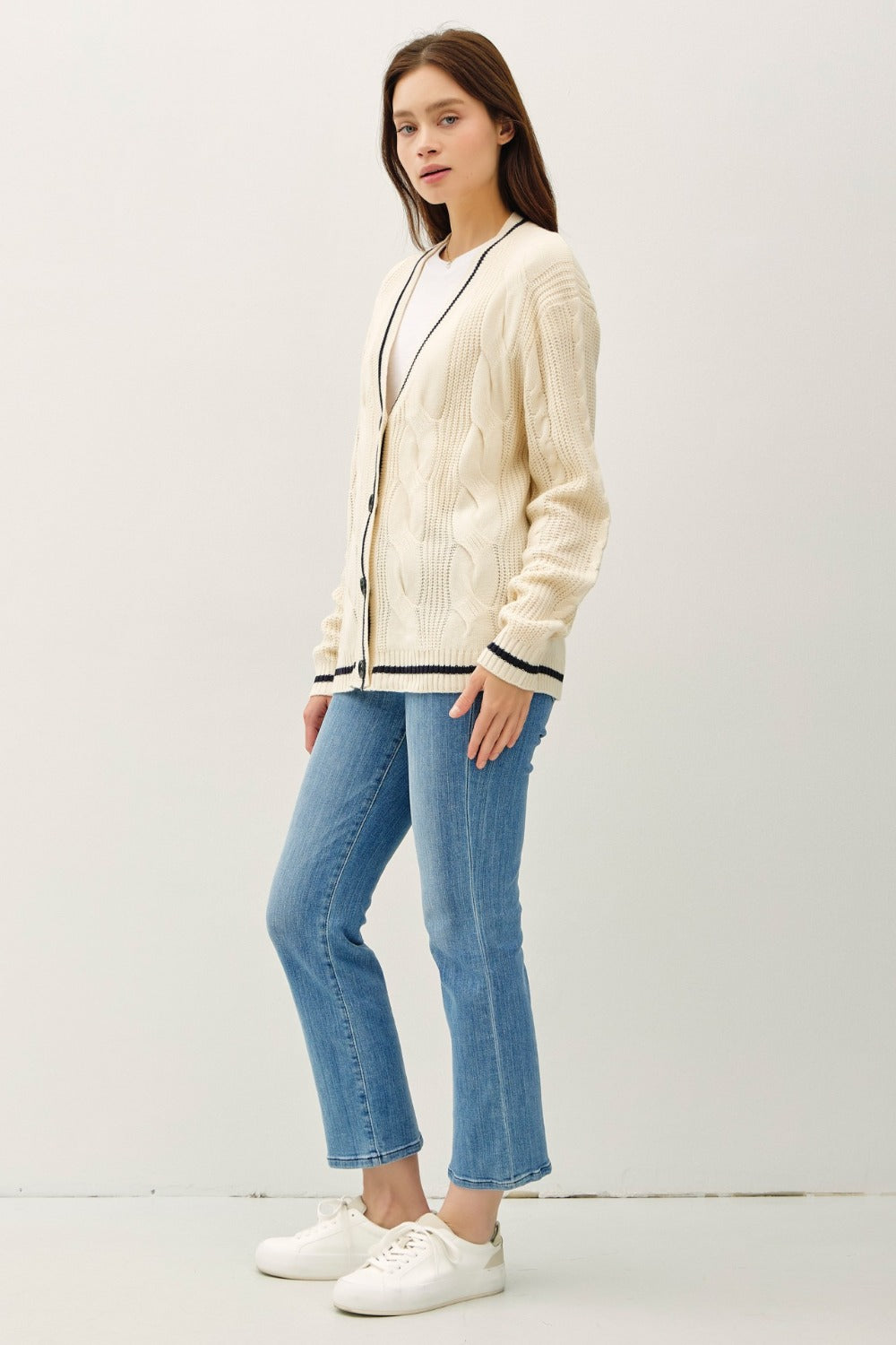 Natural and black contrast trim cable-knit cardigan with woven details and button closure.