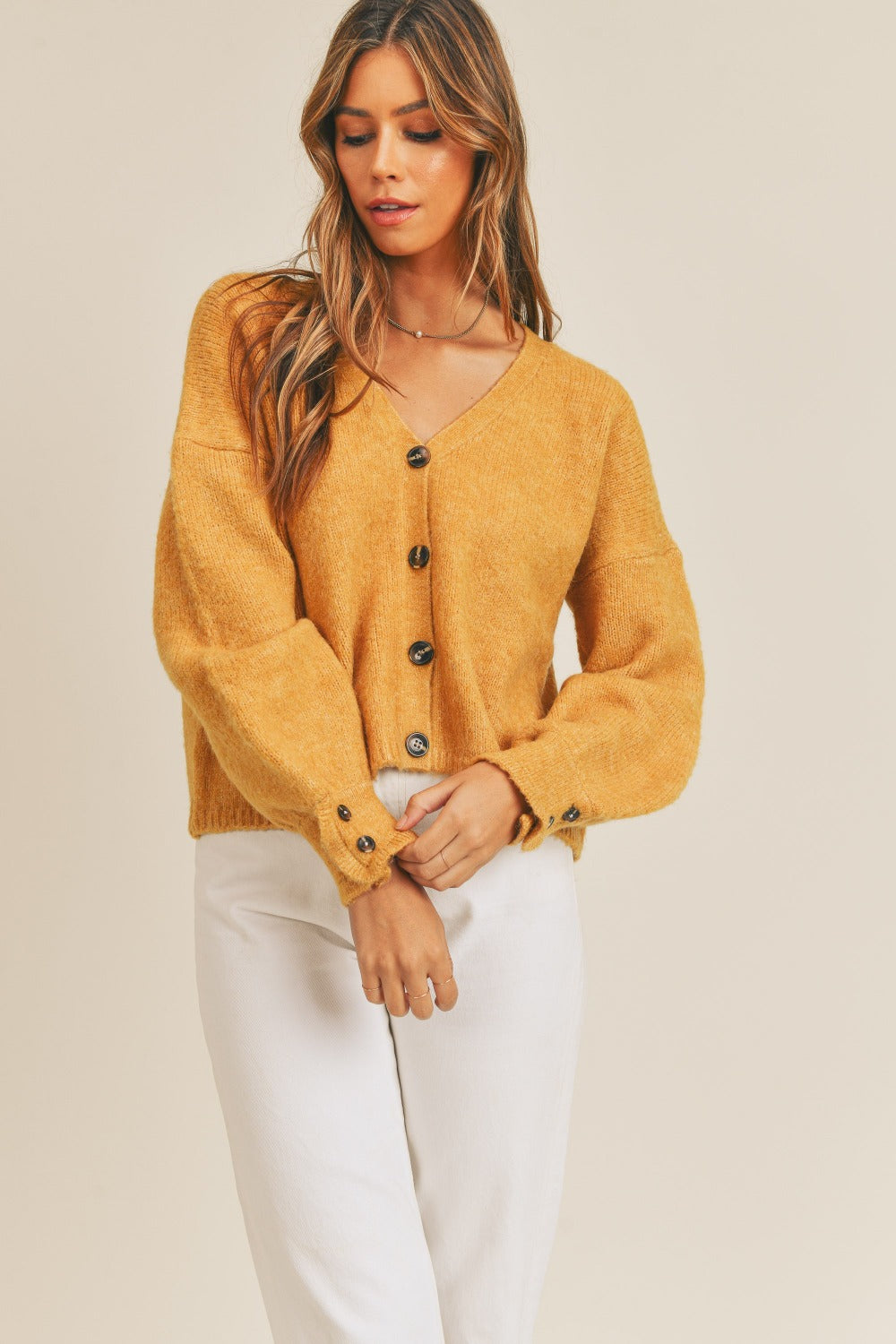 Women's mustard cardigan with a V-neckline, long sleeves, button-down closure, and a relaxed fit.