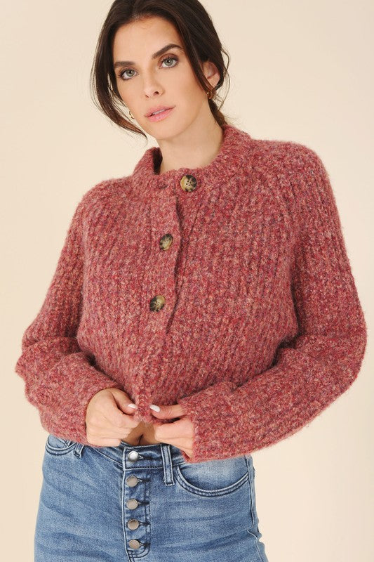 Women's button down, cropped cardigan in purple and red melange pattern with functional buttons, round neckline, and long raglan sleeves.