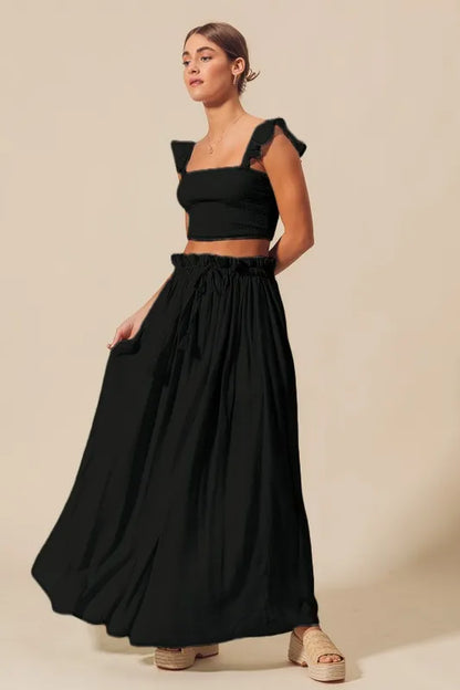Full body side view of model in Kora Smocked Top and Flowy Black Maxi Skirt Set, showing ruffled sleeve and breezy skirt movement.