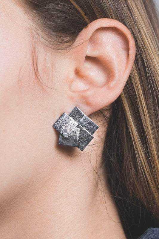 Woman wearing Square Deal Earrings in brushed gunmetal squares.