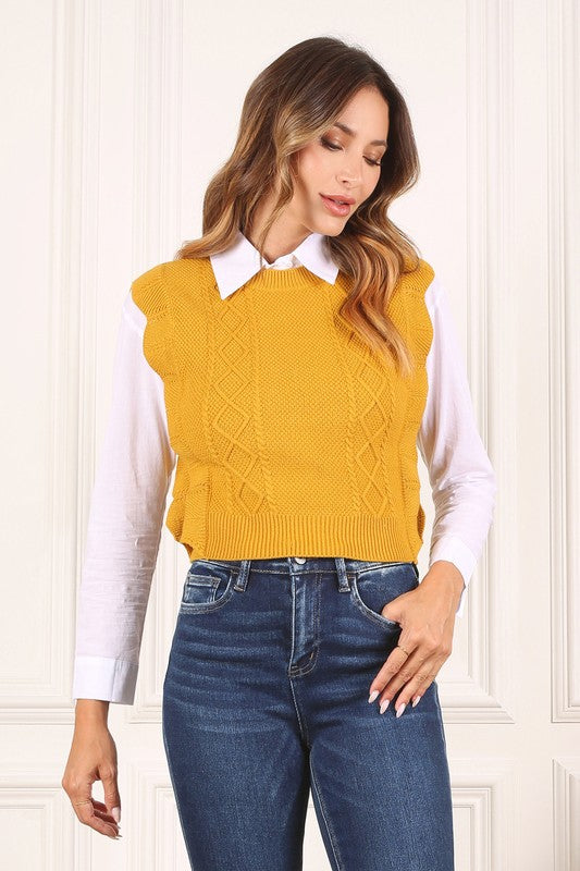 Mustard yellow sweater vest with argyle jacquard pattern, and ruffle trim on the armholes. Sleeveless with a round neckline.