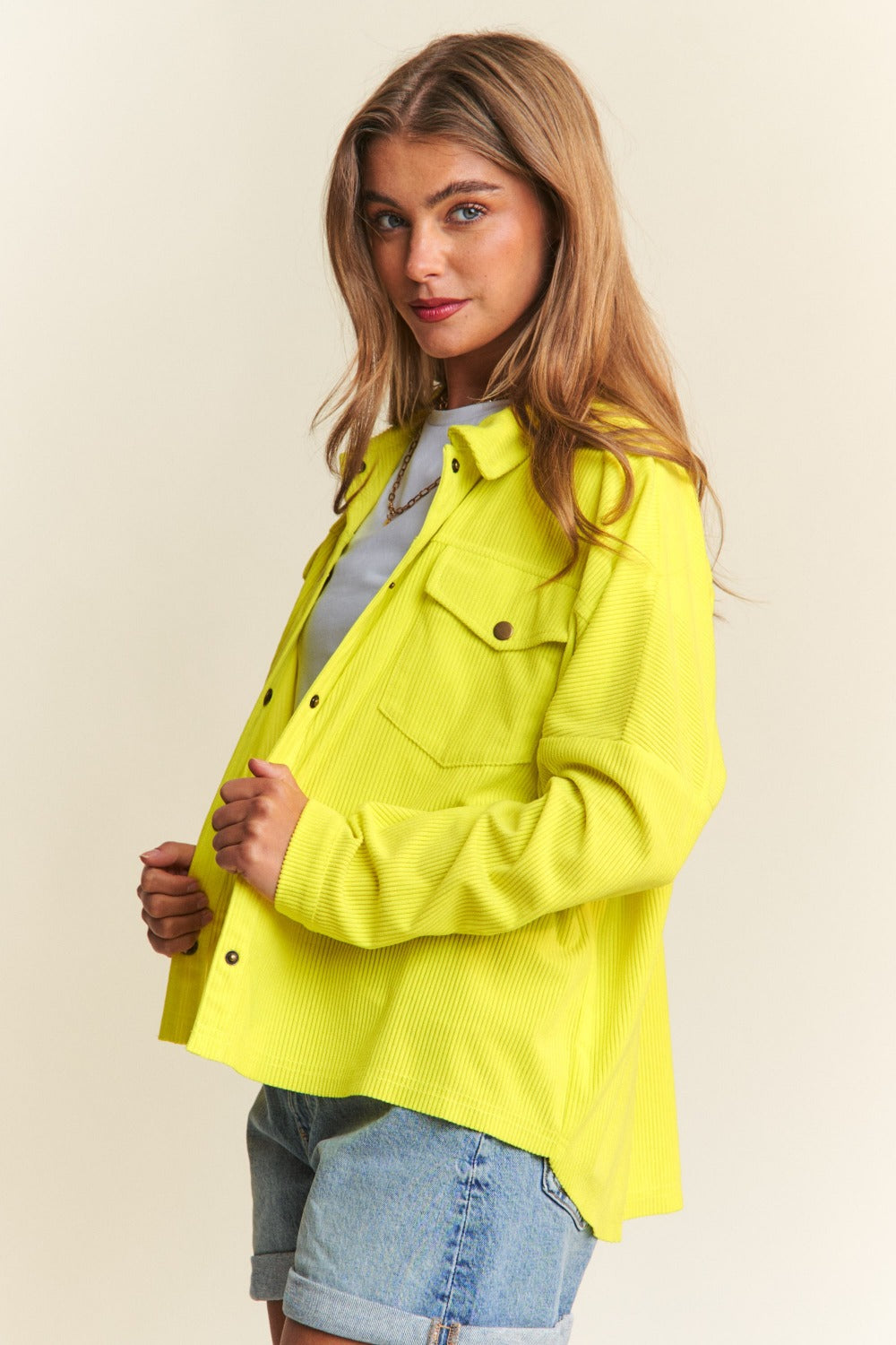 A chartreuse high-low shacket with long sleeves, a collared neckline, and snap-button closure. 