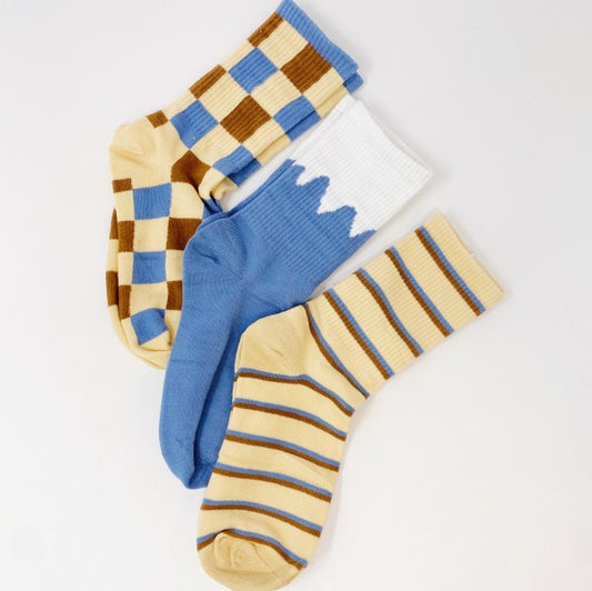 Flat lay of Trendy Pattern Trio Socks set showing checkered, striped, and snow-capped blue designs.
