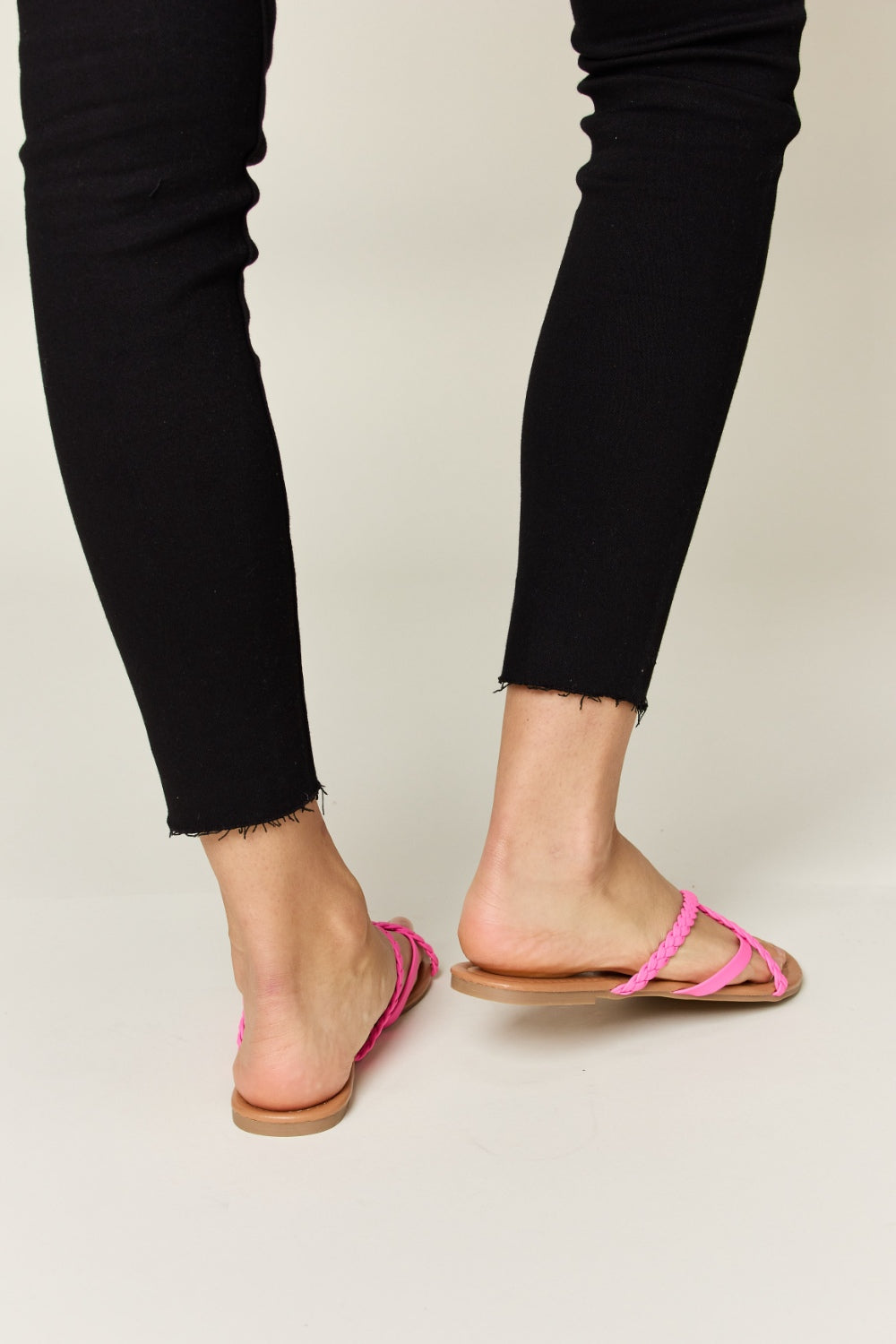 Hot pink crisscross open-toe sandals made from PU leather with a flat heel.