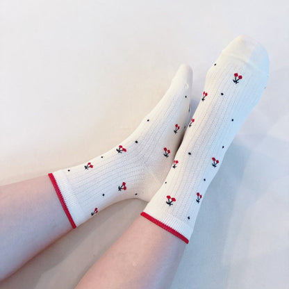 Woman wearing red-trim cherry print socks with playful all-over design.