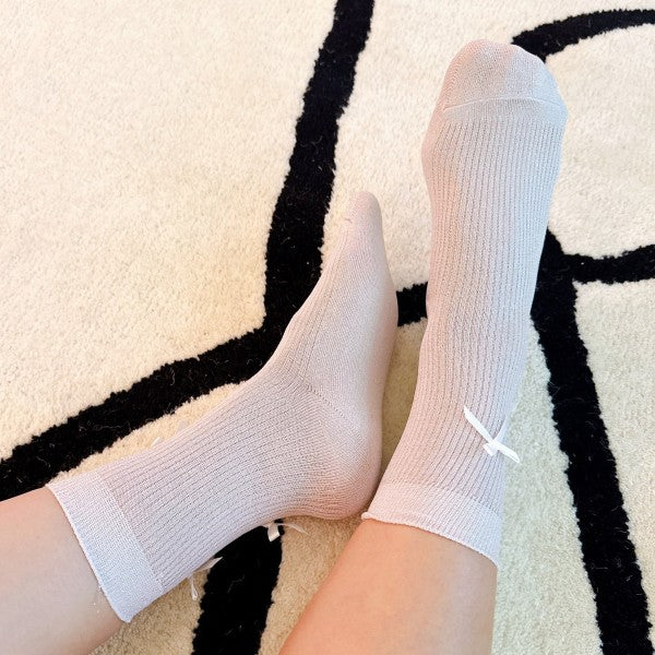 Woman wearing pink Shimmer Chic Bow Socks with satin bows and shimmer knit texture.
