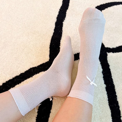 Woman wearing pink Shimmer Chic Bow Socks with satin bows and shimmer knit texture.