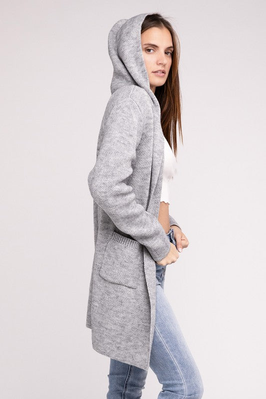 Grey sweater cardigan with long sleeves, front pockets, and a hooded neckline. 