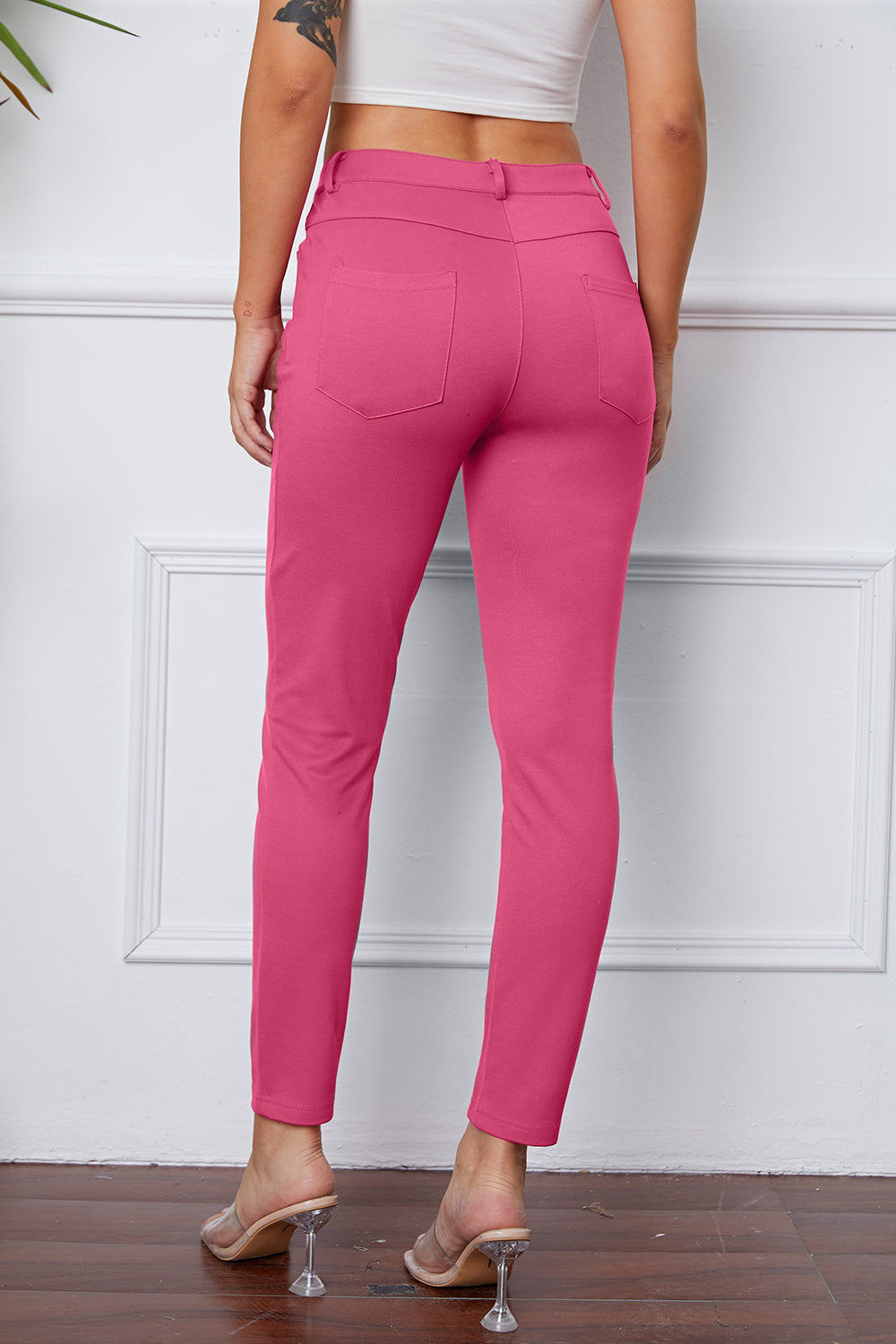 Fuchsia pink stretchy high-waisted pants feature pockets, a zip fly, and belt loops. 