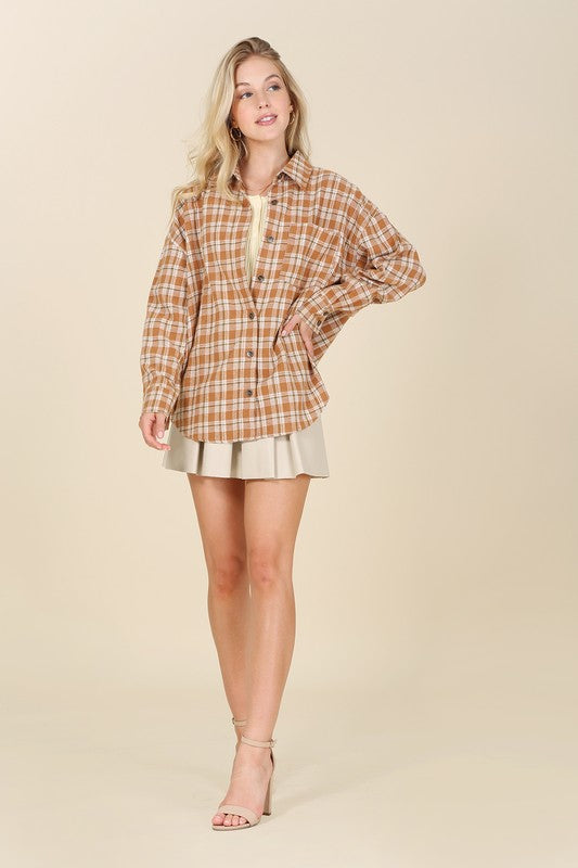 A button-front plaid shirt in rich fall colors, featuring a collared neckline, long sleeves with drop shoulders, and a chest pocket. 