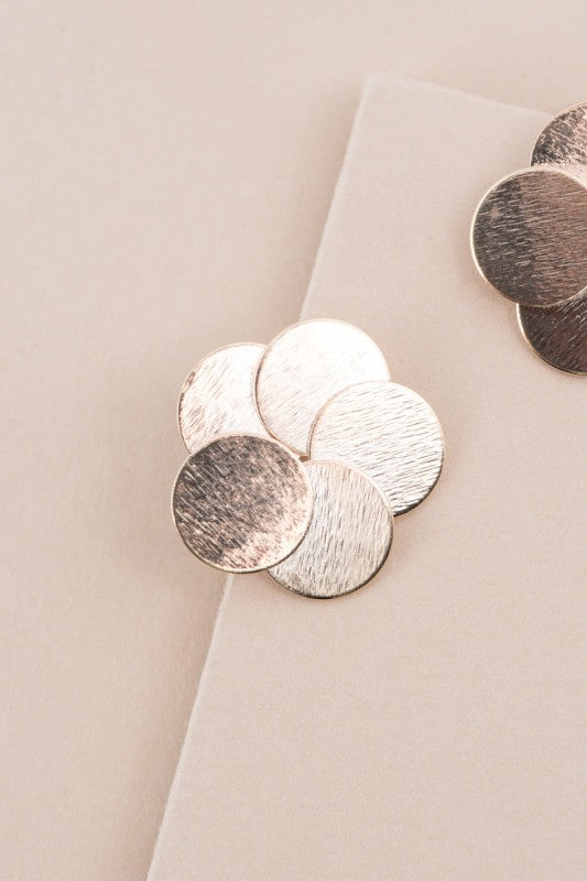 Close-up of Round and Round Earrings with textured brushed gold finish.