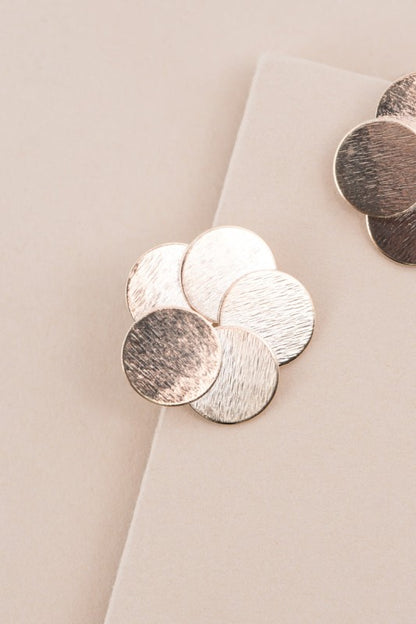 Close-up of Round and Round Earrings with textured brushed gold finish.