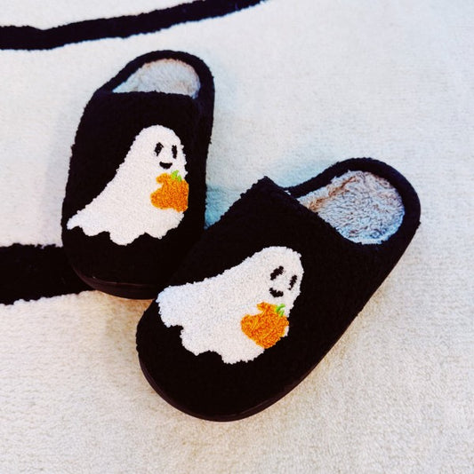 Pair of Spooky Ghost Cozy Slippers in black with cute white ghost holding a pumpkin design and plush lining.