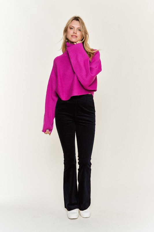 Full body front Giada Mock Neck Wide Sleeves Sweater in fuchsia with sneakers.
