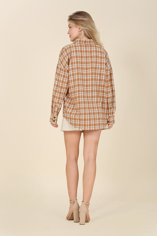 A button-front plaid shirt in rich fall colors, featuring a collared neckline, long sleeves with drop shoulders, and a chest pocket. 