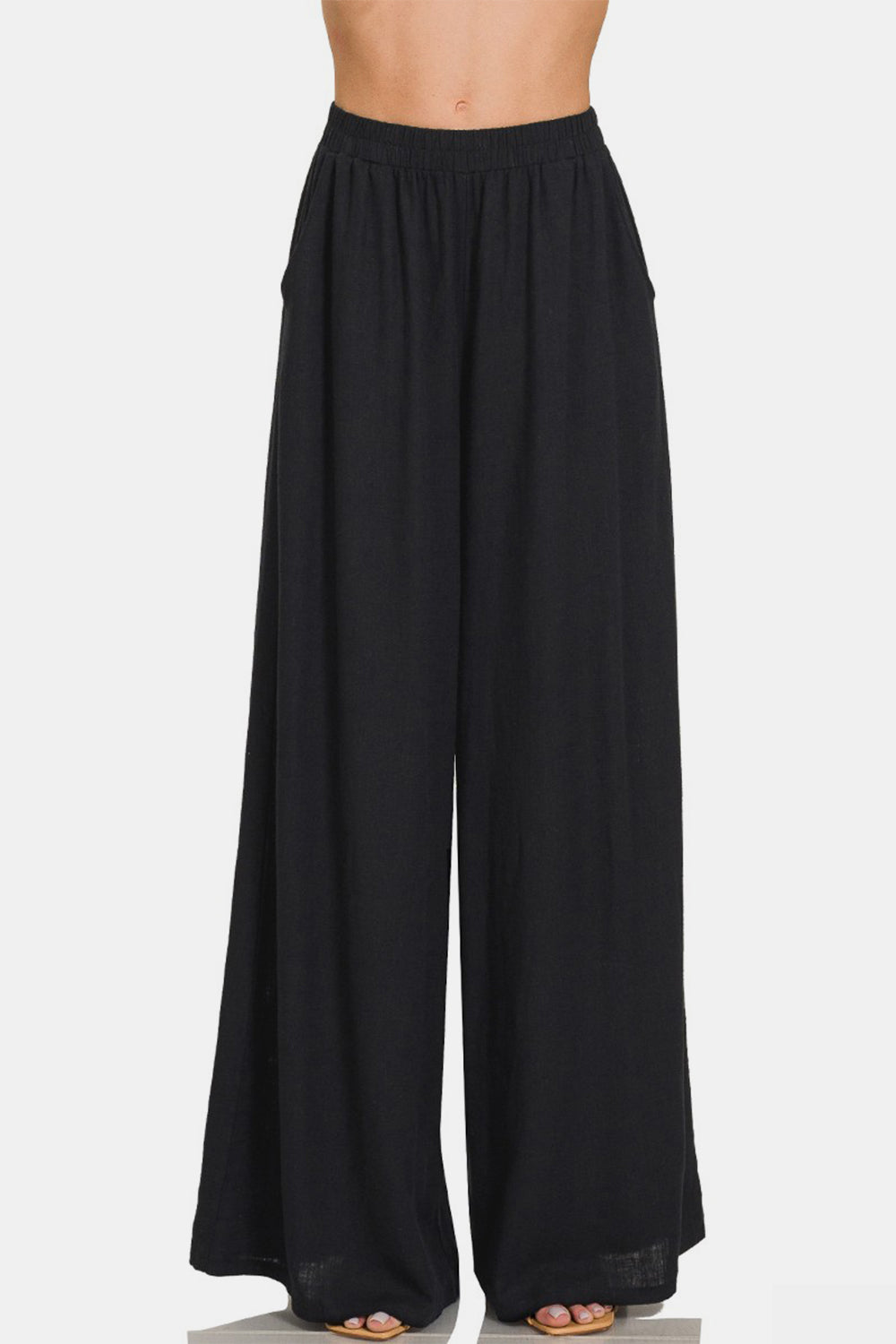 Black high-waisted pleated wide leg pants, elastic waist, made from a linen blend fabric.