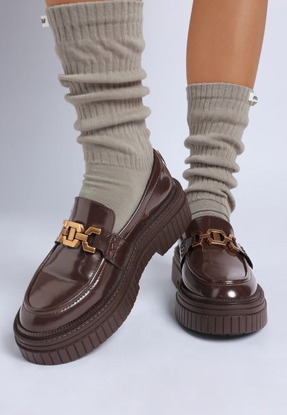Close-up of brown Grosbeak Horsebit Chunky Loafers with gold chain detail.