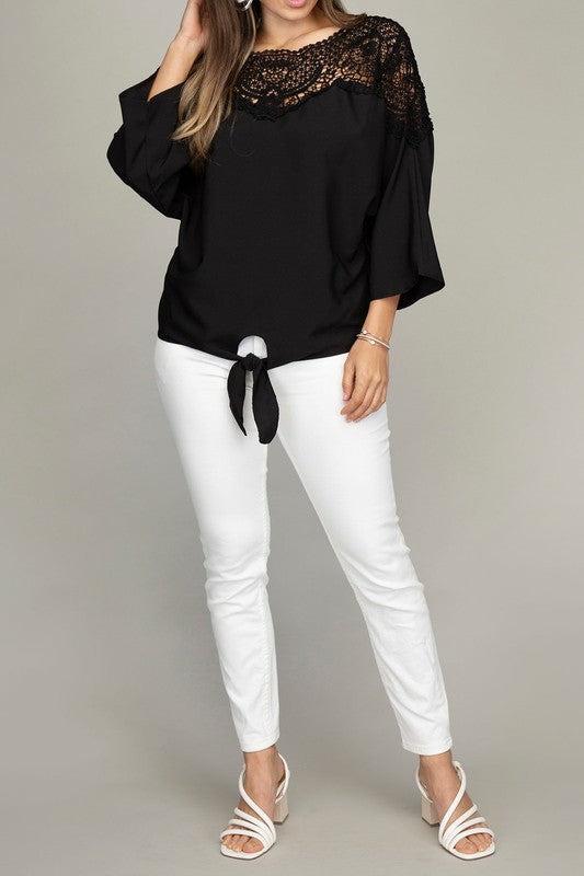 Black blouse with lace trim, a tie neckline, and relaxed three-quarter dolman sleeves.