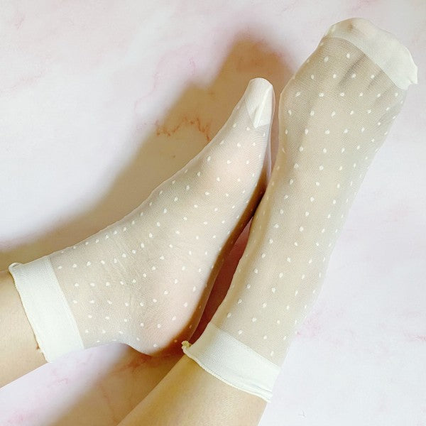 Woman wearing white sheer socks with delicate dot pattern and stretchy fit.