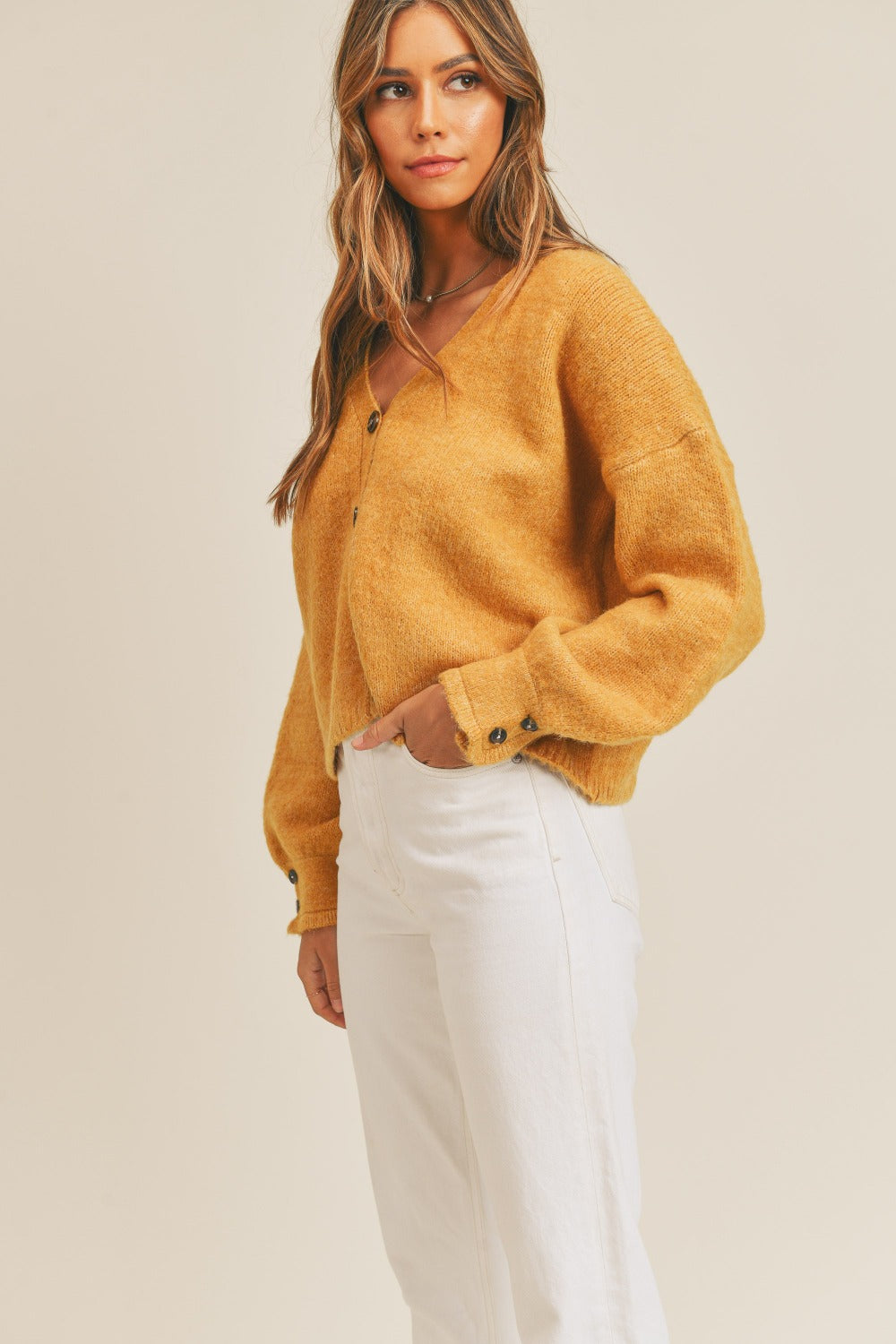 Women's mustard cardigan with a V-neckline, long sleeves, button-down closure, and a relaxed fit.