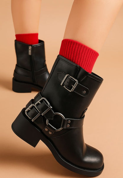 Model wearing black Caribou Biker Boots with edgy harness detail and block heel.