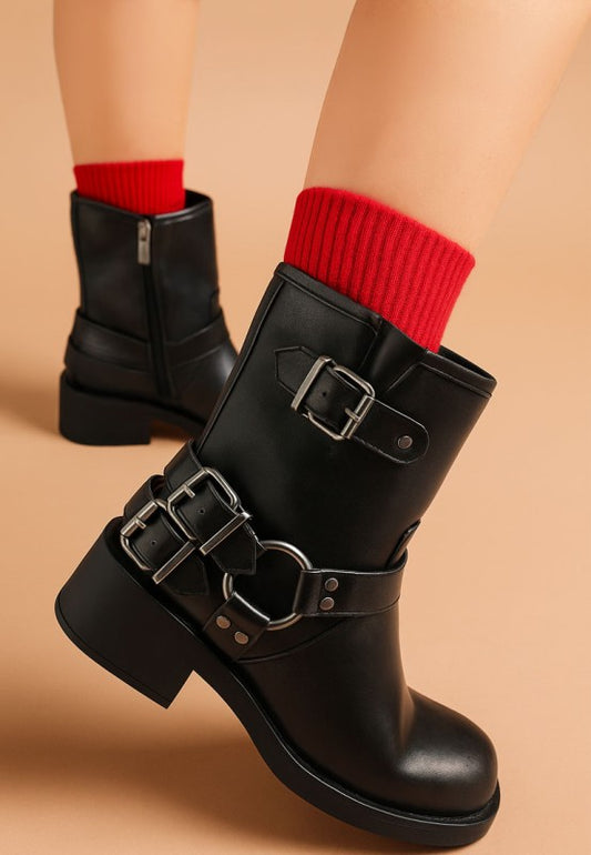 Model wearing black Caribou Biker Boots with edgy harness detail and block heel.