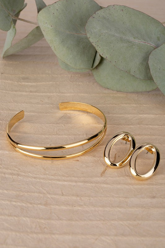 Gold oval earrings and a matching cuff bracelet.