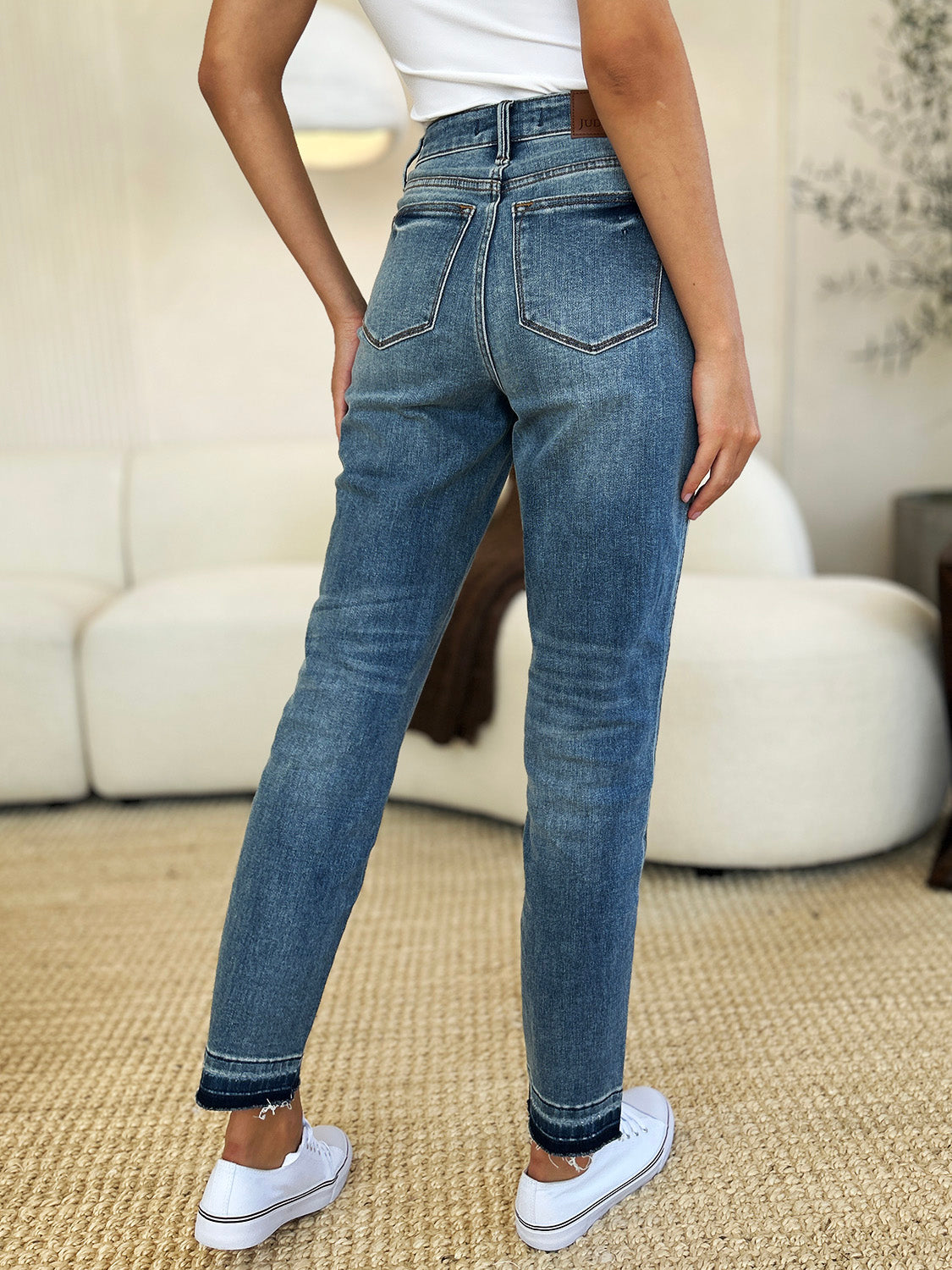 Medium wash mid-rise jeans with rigid fabric and released hem detail, featuring a relaxed fit and moderate stretch by Judy Blue.