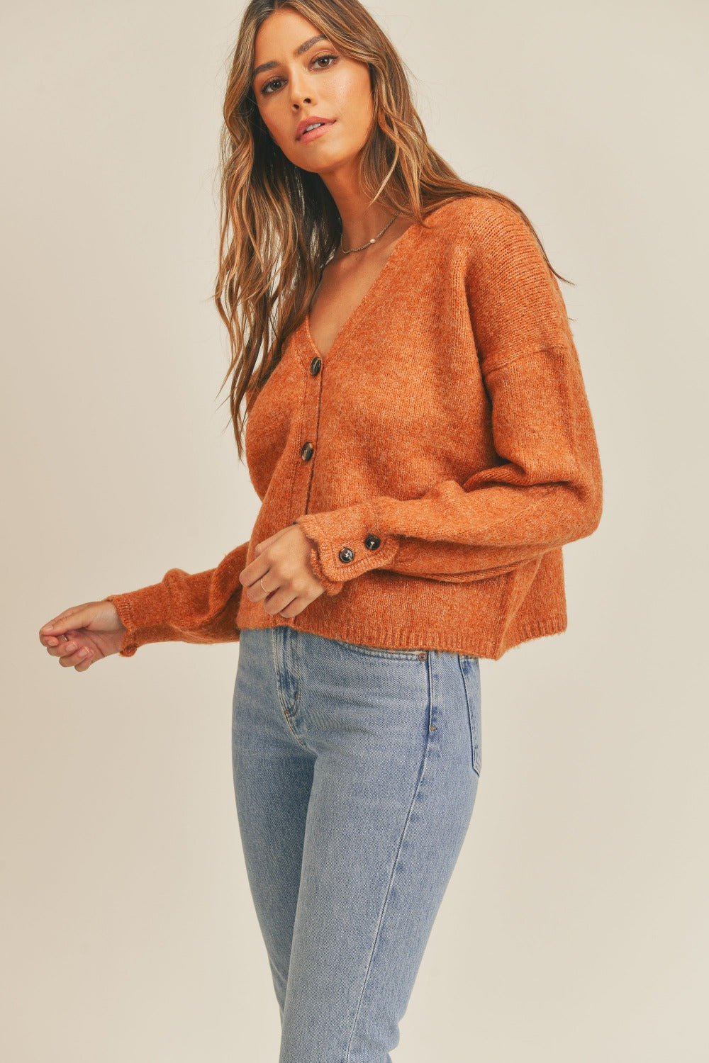 Women's rust colored cardigan with a V-neckline, long sleeves, button-down closure, and a relaxed fit.