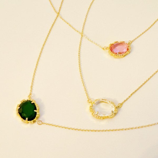Clustered Glass Jewel Necklaces in clear, emerald, and pink on gold chains, displayed together flat lay.
