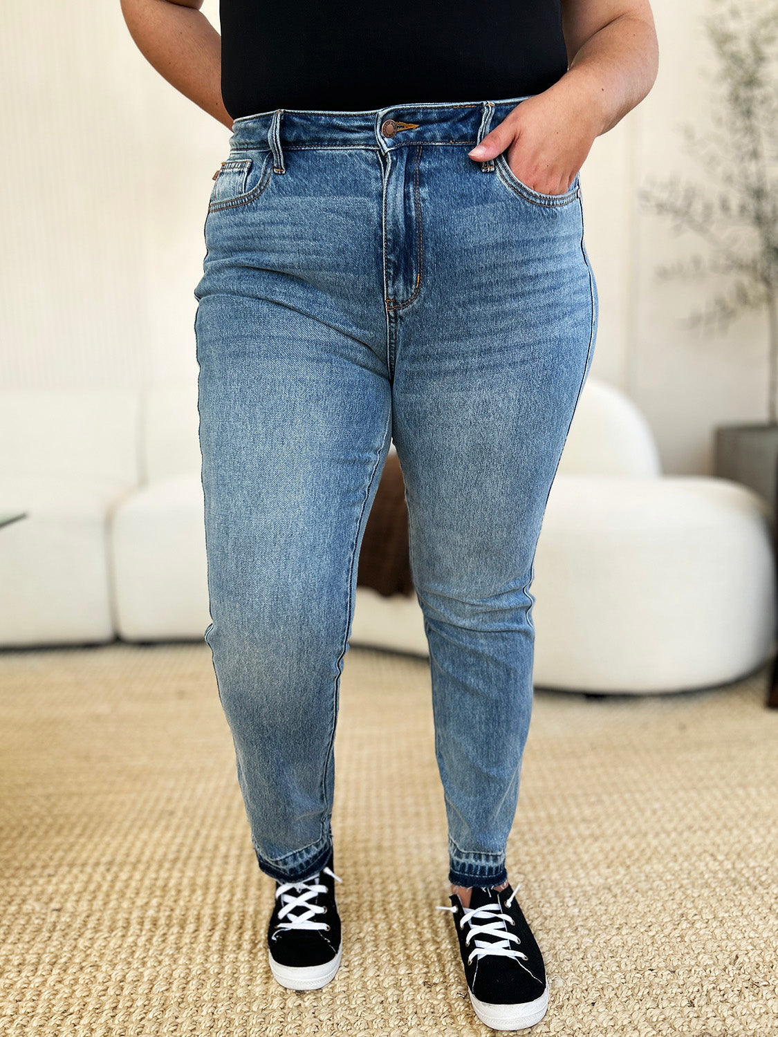 Medium wash mid-rise jeans with rigid fabric and released hem detail, featuring a relaxed fit and moderate stretch by Judy Blue.