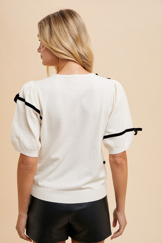Back view of the Bernadette Striped Bow Knit Top in white with black stripes, featuring a feminine bow, round neckline, short sleeves, and ribbed knit for a chic, comfortable style.
