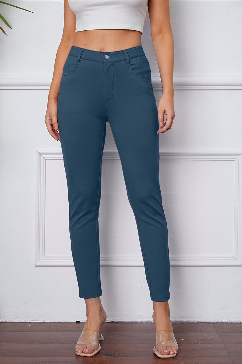 Dusty blue stretchy high-waisted pants feature pockets, a zip fly, and belt loops. 