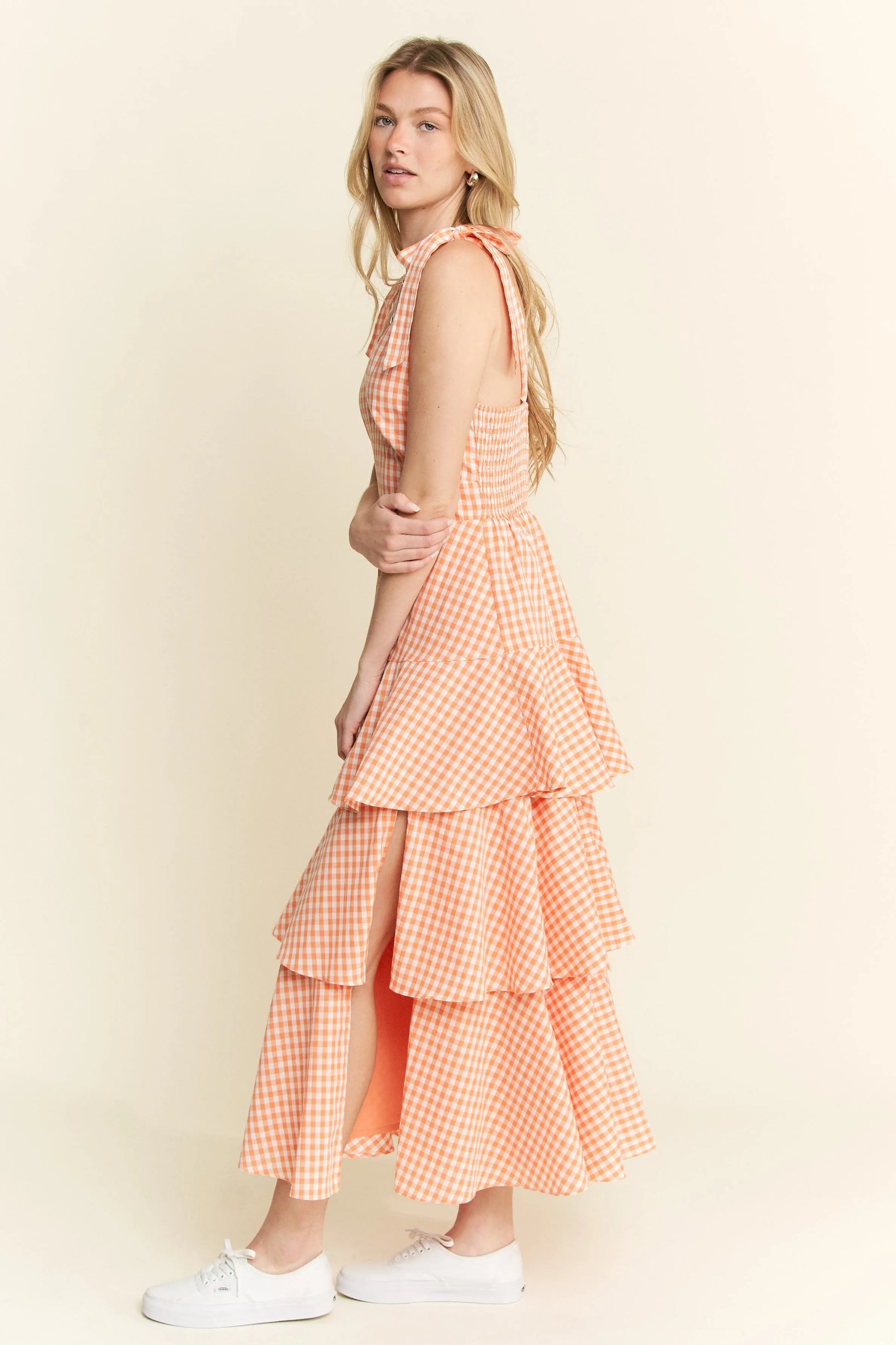Full body side view of model wearing Alice Gingham Tiered Midi Dress by Jade by Jane, featuring ruched back, halter ties, and layered ruffle skirt.