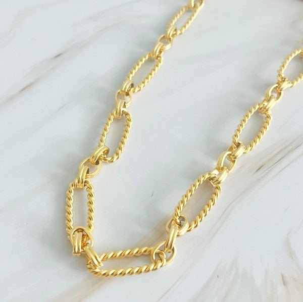 Close-up view of alternating twisted and smooth cable links in gold necklace