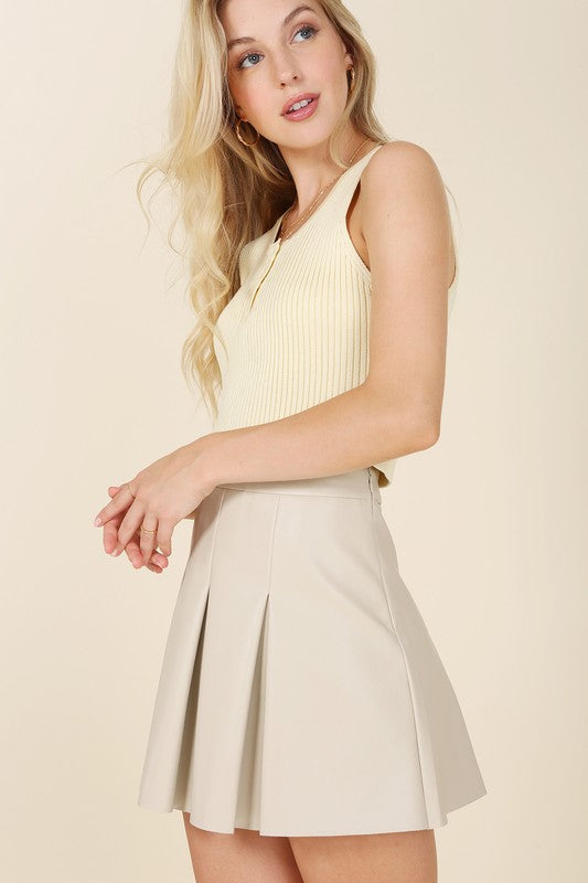 Ivory vegan leather pleated mini skirt with 4 pin tucks on the front and back for added style. Features a zipper closure.