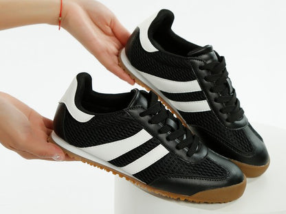 Side angled view of model holding black Blaster sneakers with white stripes, showing mesh texture and lug sole – lightweight sporty design by Rag Company