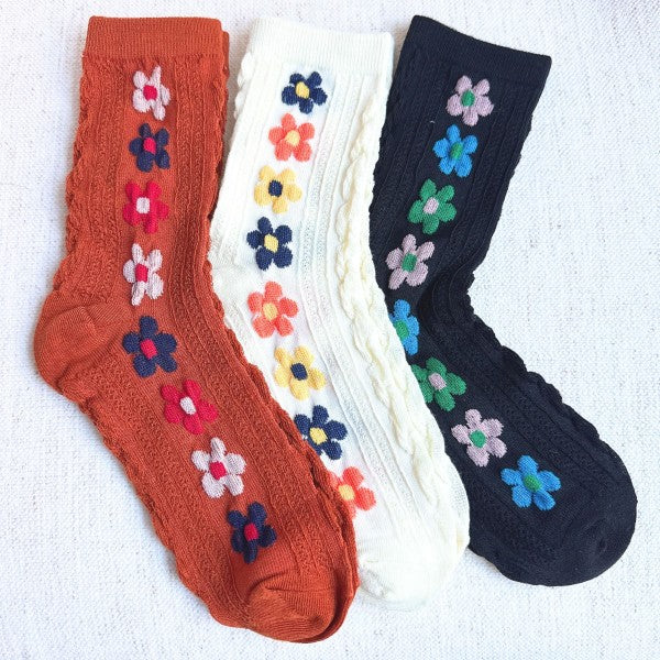 Flat lay of Side Garden Flower Socks Set of 3 in camel, white, and black with floral patterns.