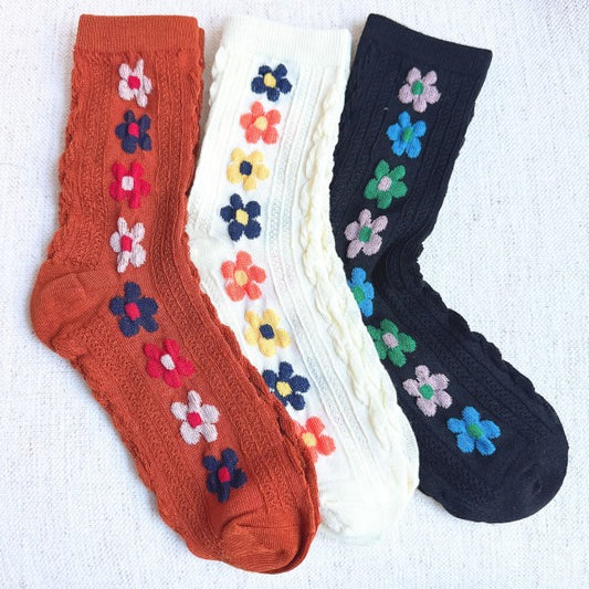 Flat lay of Side Garden Flower Socks Set of 3 in camel, white, and black with floral patterns.