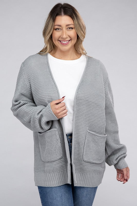 Curvy plus-size waffle-pattern open cardigan sweater in light grey, with long sleeves, oversized fit, and pockets.