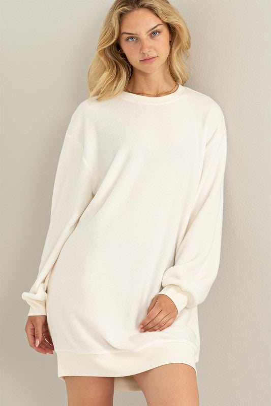 Cream-colored girlfriend sweatshirt mini dress with a crew neckline and cuffed hem, drop shoulders, long sleeves, and a relaxed fit. 