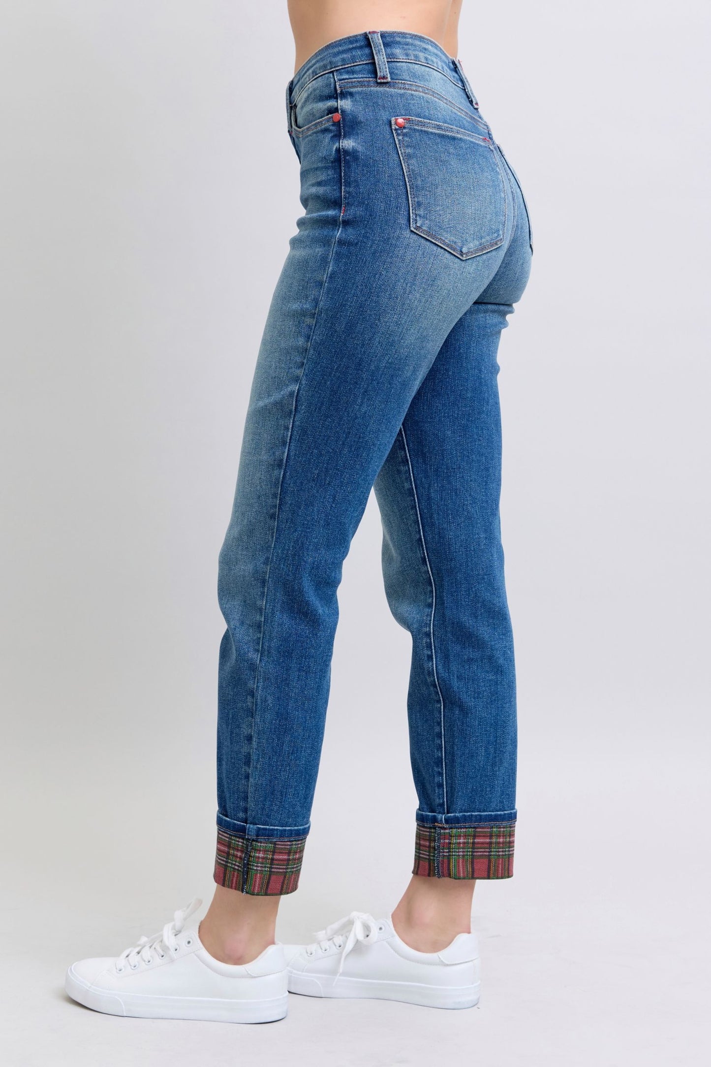 Women's mid rise, medium-wash straight-leg jeans with red and green plaid cuffs.