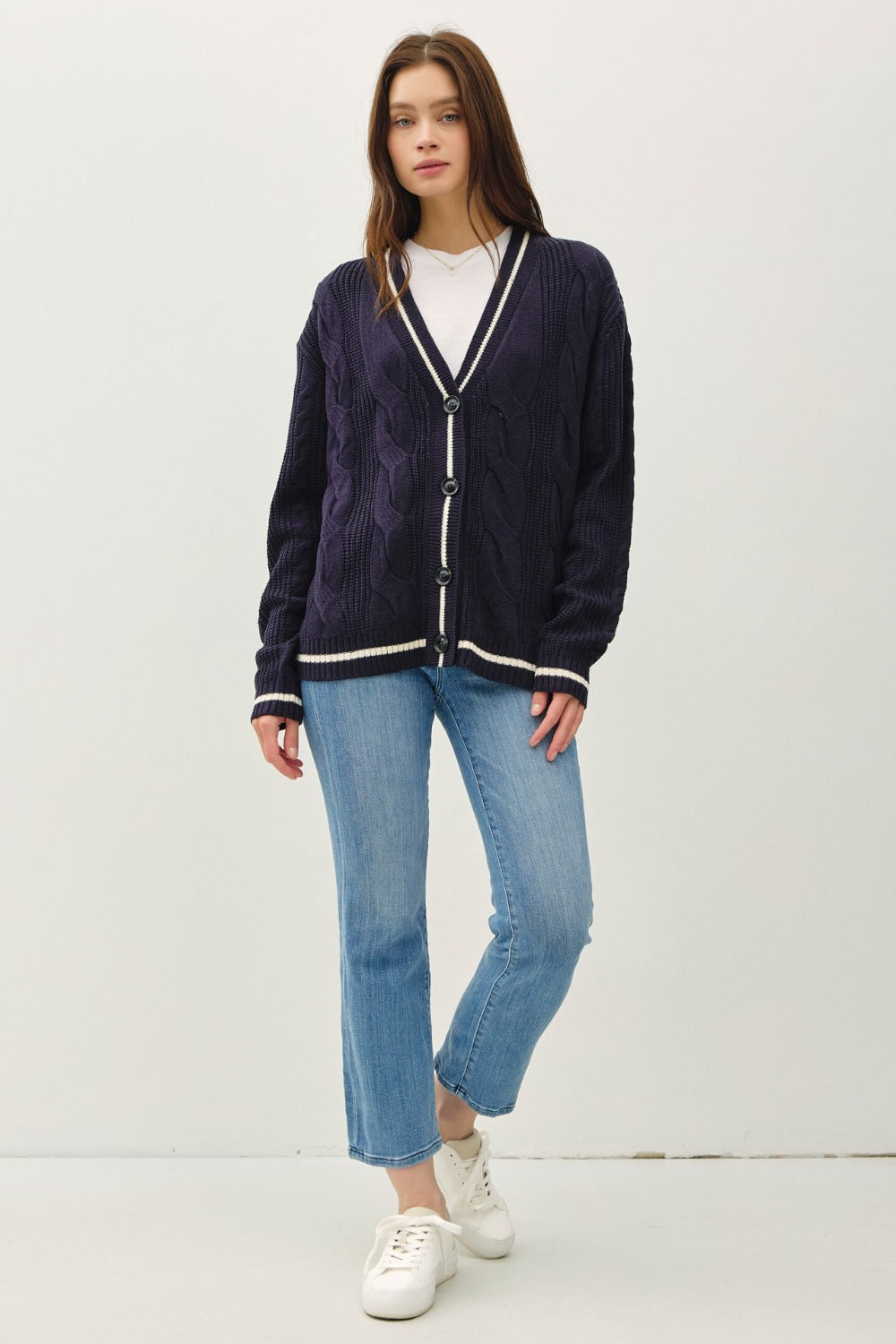 Navy and white contrast trim cable-knit cardigan with woven details and button closure.