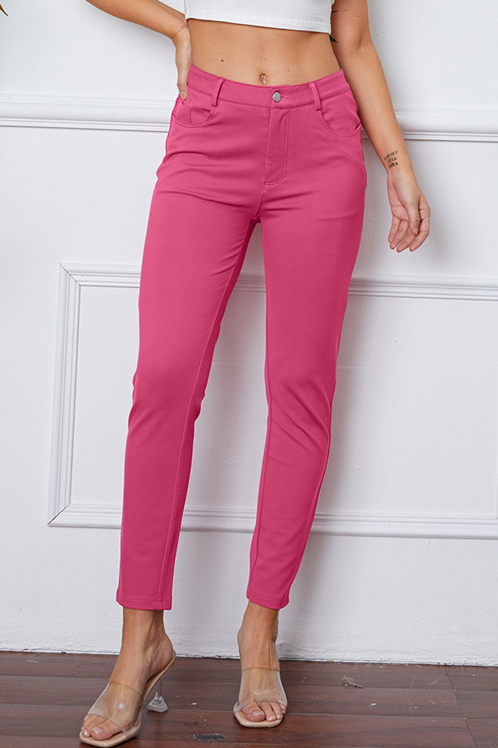 Fuchsia pink stretchy high-waisted pants feature pockets, a zip fly, and belt loops. 