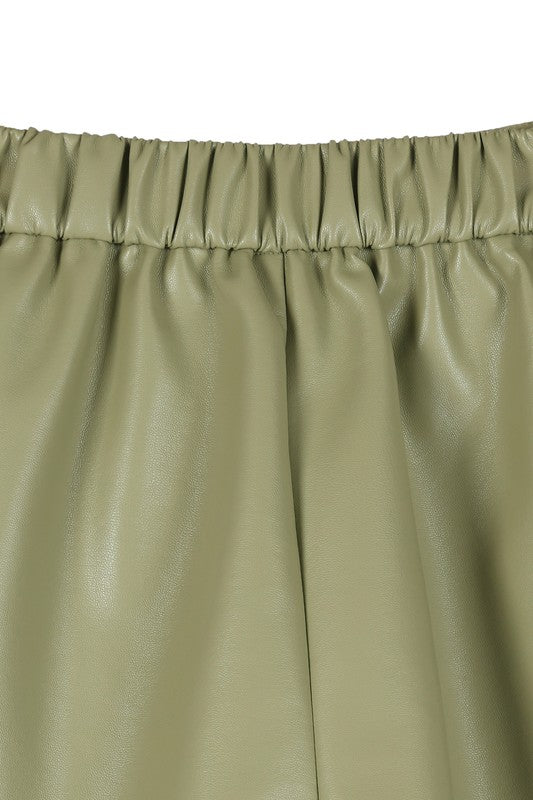 Trendy green vegan leather shorts featuring a hook and zipper closure, side pockets, pin-tuck detailing, and a comfortable wide elastic waistband.