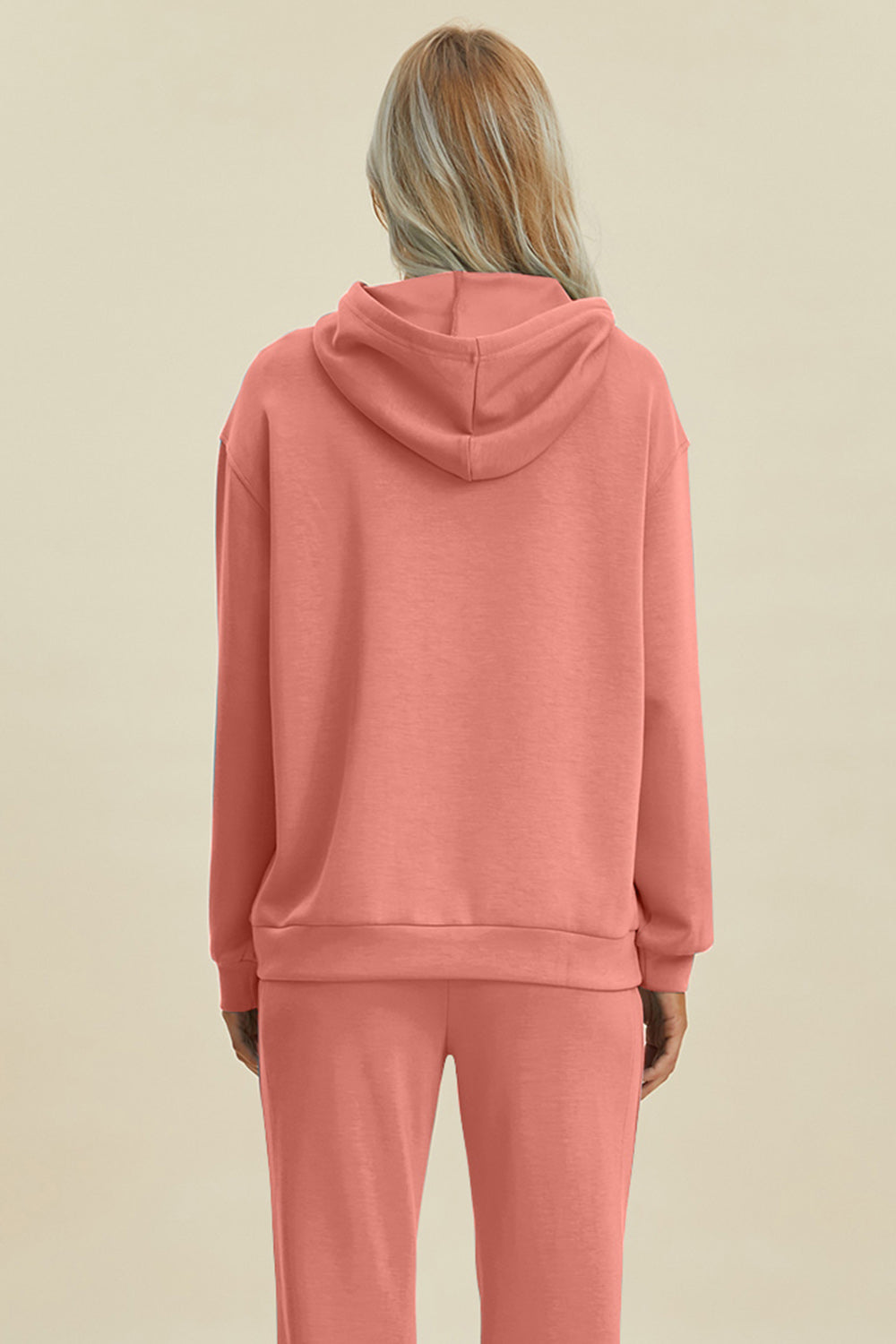 Coral long sleeve hoodie with kangaroo pocket, featuring a drawstring hood andrelaxed fit.