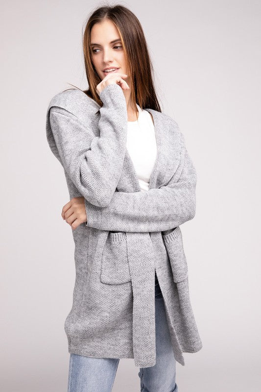 Grey sweater cardigan with long sleeves, front pockets, and a hooded neckline. 